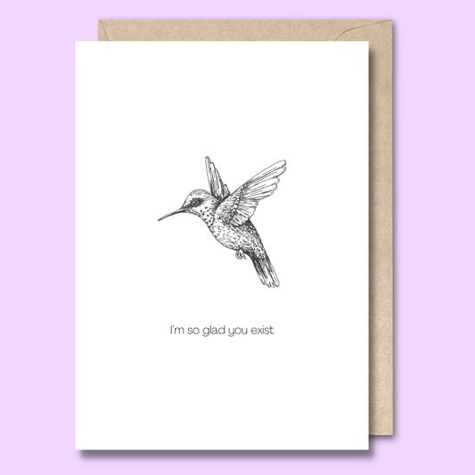 Front of a plain white greeting card with a black and white sketch of a cute hummingbird in the middle. The text says "I'm so glad you exist."