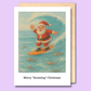 A greeting card with santa waving as he surfs over dead fish