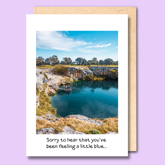 Greeting card featuring a photo of people jumping into Little Blue Lake near Mount Gambier, South Australia on a clear blue day. The text below the image says 'Sorry to hear that you've been feeling a little blue'.