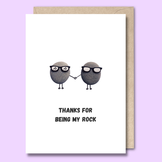 Front of a plain white greeting card with two rocks in the middle of the card wearing sunglasses and holding hands. The text below the image says "Thanks for being my rock."