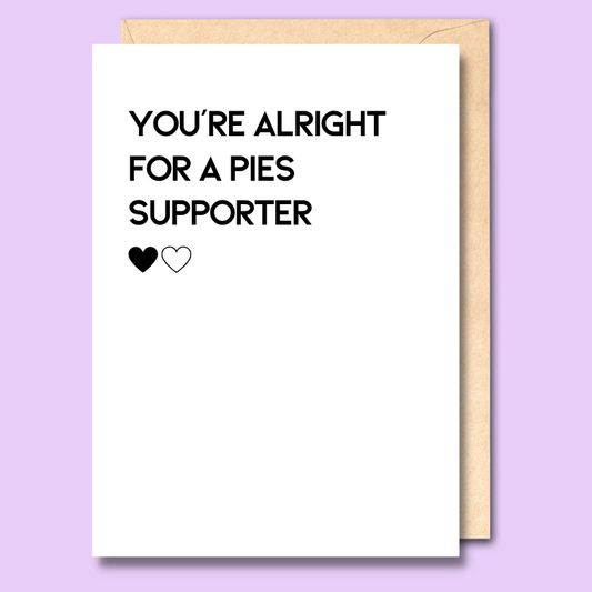A white greeting card that says 'You're alright for a Pies supporter'