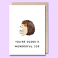 Front of a plain white greeting card with a watercolour style image of a happy hedgehog wearing headphones in the middle. The text below the image says "You’re doing a wonderful job."