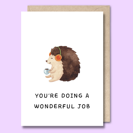 Front of a plain white greeting card with a watercolour style image of a happy hedgehog wearing headphones in the middle. The text below the image says "You’re doing a wonderful job."