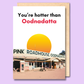 A white greeting card with a photo of the pink roadhouse in Oodnadatta on it. The text on the front says "You're hotter than Oodnadatta".